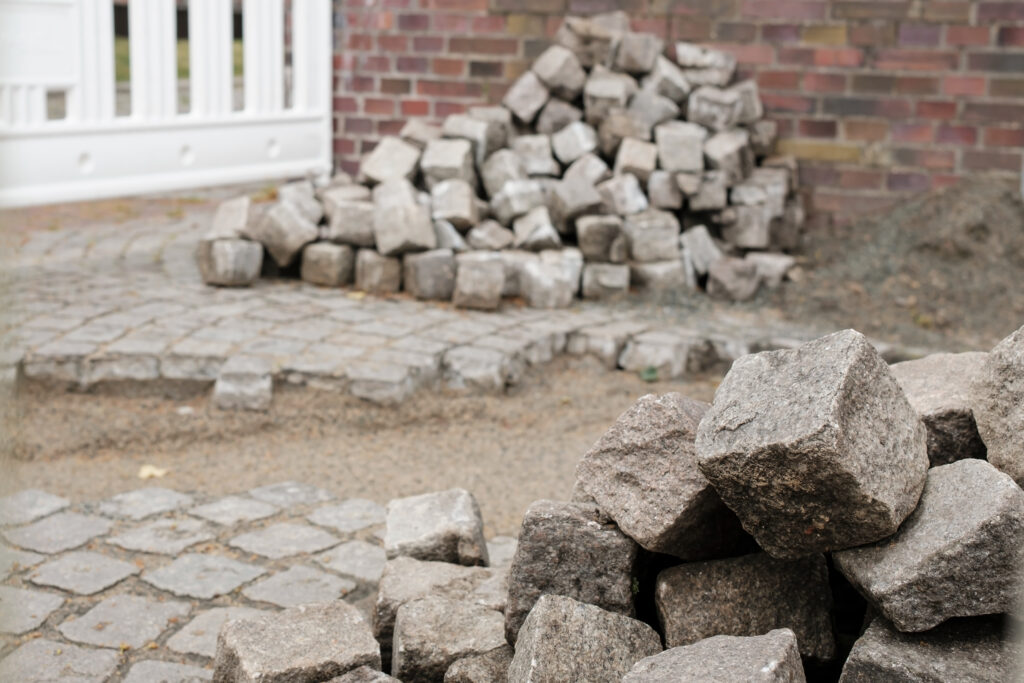 A stone walkway with stones removed from the middle of the path and placed in piles on either side.